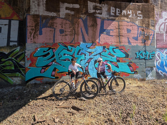 Gravel riders on HiFi wheels in front of a graffiti wall on the Frogger route.